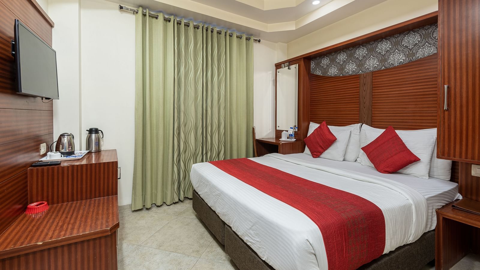 Side view of a deluxe room featuring a king size bed, a TV, and a tea & coffee maker on the table at DLS Hotels The Rock Castle.